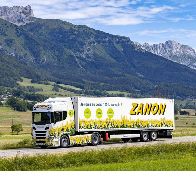 Camion de l’entreprise Zanon sur une petite route avec une chaine de montagne au loin 