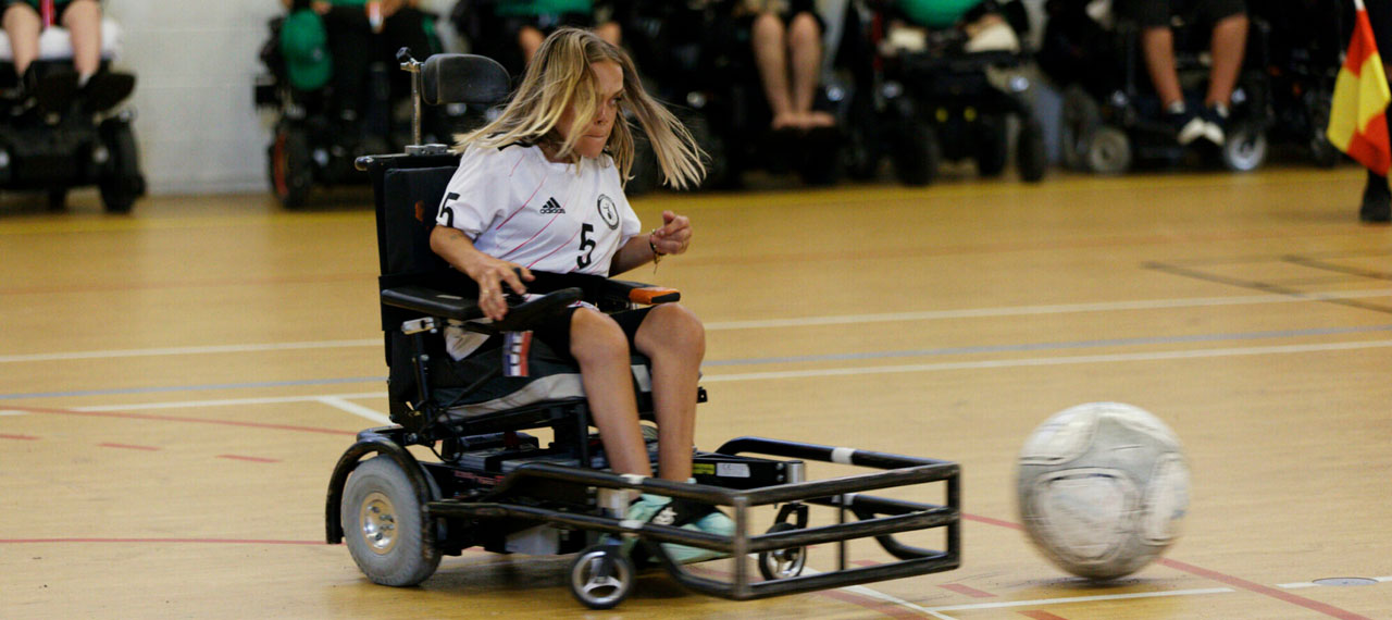 Compétition de Foot-Fauteuil. Une participante dans son fauteuil adapté vient de percuter le ballon.