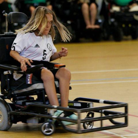 Compétition de Foot-Fauteuil. Une participante dans son fauteuil adapté vient de percuter le ballon.